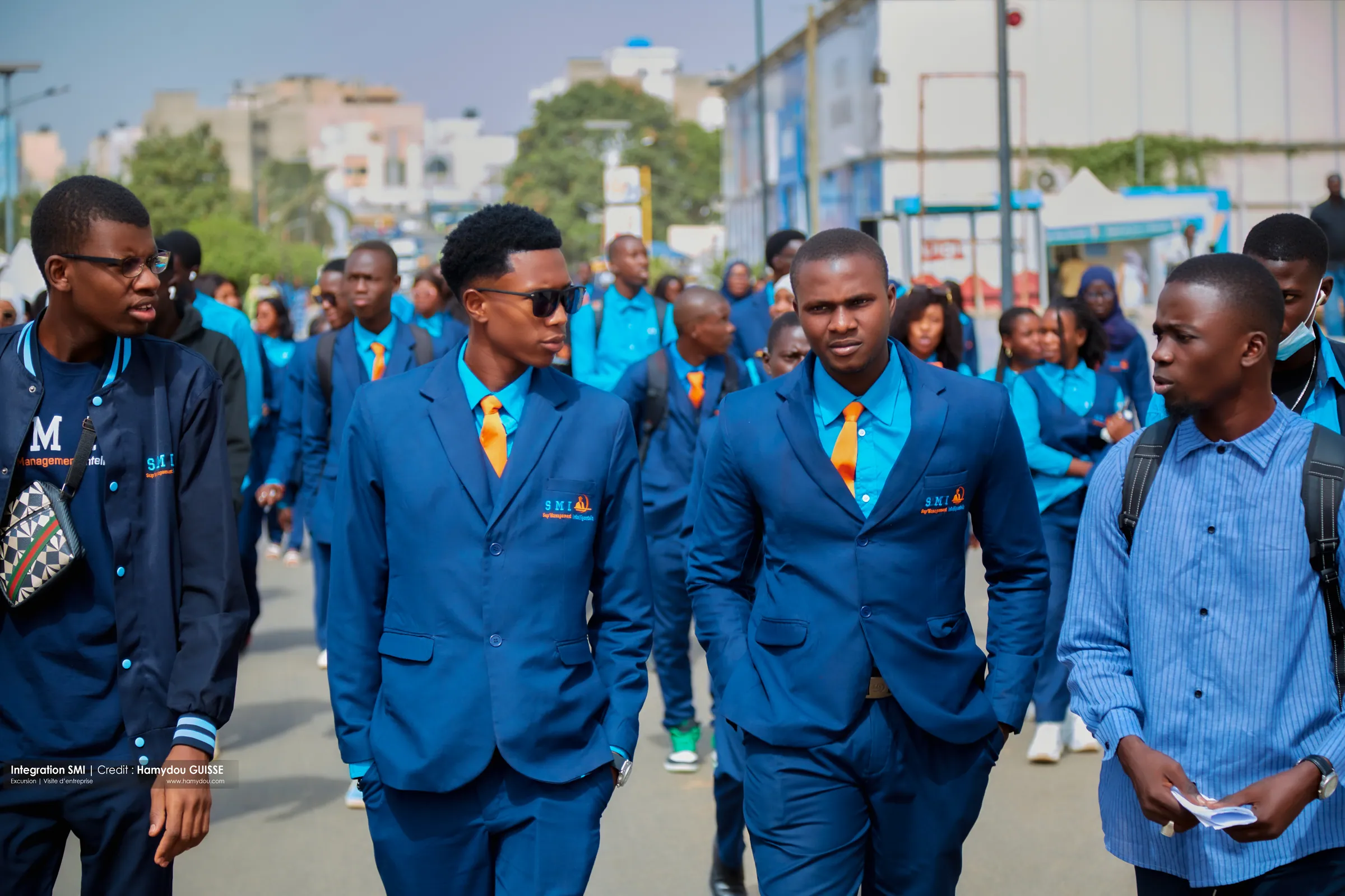 Étudiants de SMI en blazer bleu et foulard orange marchant lors de la visite à Dakar